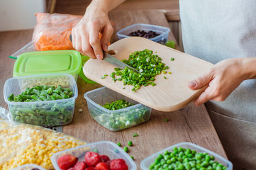 Close up of woman cutting green onion for freezing in the plastic food box