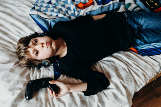 boy playing video games on the bed in his room