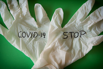 Sanitary gloves with the written words Covid 19 and stop on a green background