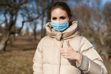 Prevention of coronavirus outbreak in 2020. Outdoor portrait of young european woman wearing a disposable facial mask. Prevent pollution and disease concept.