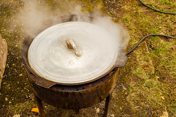 cauldron at the stake, there is steam from under the lid