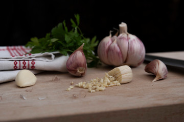 Clove of garlic on a cutting board with a knife and an old tea towel