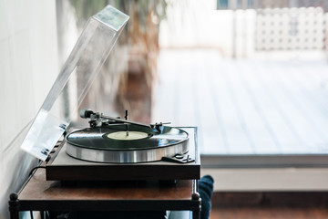 vinyl record turntable on wooden base playing a vinyl record