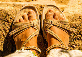 Feet with sandals full of desert sand, adventure