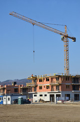 Two apartment houses under construction with yellow tower crane above construction site