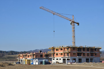 Two apartment houses under construction with yellow tower crane above construction site