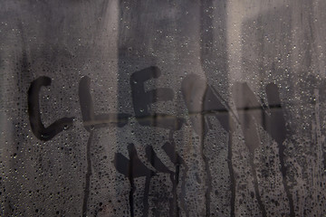 letters CLEAN on the glass. handwritten lettering written on glass with white foam on gray stuface...