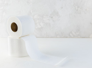 Rolls of white toilet paper on a white table. Horizontal orientation, copy space.