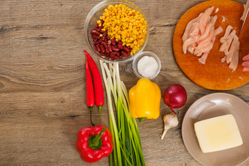 Ingredients for Burritos, chicken meat, corn, tomatoes and peppers on wooden background. Top view