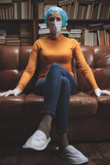 Woman with protective antiviral mask sitting at home in isolation / quarantine.
