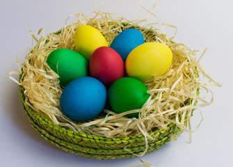 Naklejka na ściany i meble Colored eggs in a green basket
