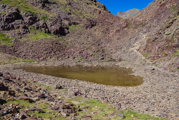 Small glacial lake surrounded by rocks in Coma Pedrosa in Andorra