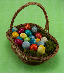 Easter, colored painted eggs in a wicker basket with moss