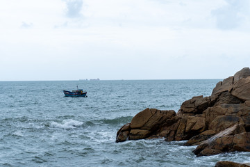 Rock, fisherman's boat and sky in Qui Nhon, Vietnam