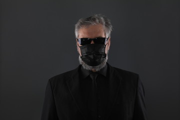 close-up studio portrait of a man in a black medical mask from coronavirus on a black background