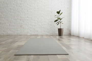 Unrolled grey yoga mat on floor in room