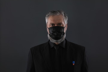 close-up studio portrait of a man in a black medical mask from coronavirus on a black background