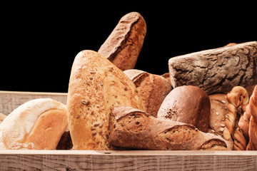 Fragrant bread on the table. Food concept in a wooden box on black background