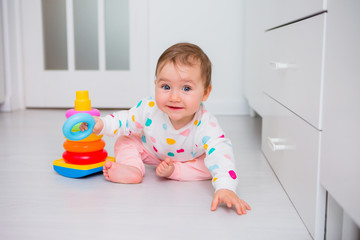 Toddler girl plays educational games at home. Baby sits on the floor of the house