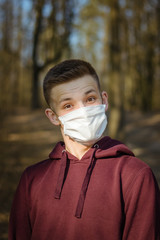 Closeup portrait of a young guy in a disposable medical mask. Pandemic. Coronavirus. Quarantine. The young man in the mask.