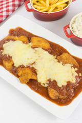 Veal parmigiana in a white platter with rice in and french fries in white background seen from above vertical