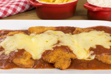 Veal parmigiana in a white platter in wood background close