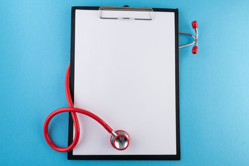 Stethoscope (red) and blank clipboard with a sheet of white paper on it with a place for text on light blue backround. Medical mockup or template.