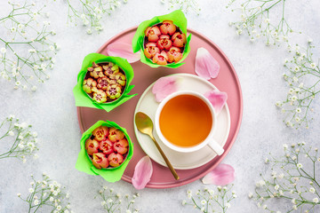 A cup of tea and cupcakes with tulips on white background