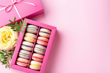 Colorful macaroons and flowers. Sweet macarons in gift box. Top view