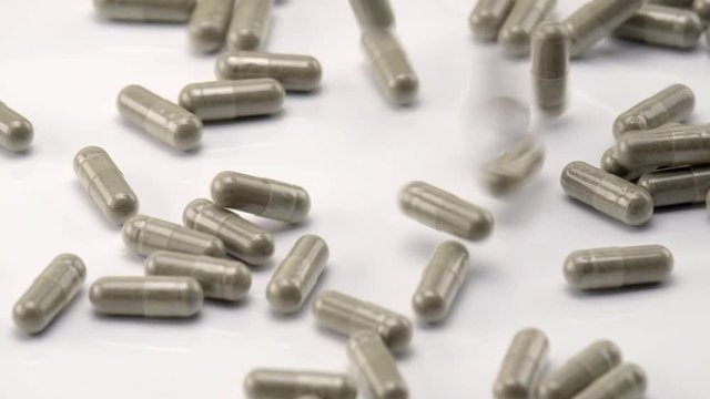 Close Up View of Natural Herbs Capsules Falling and Bouncing on White Background.