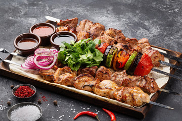 Kebabs - grilled meat skewers, shish kebab with vegetables on black wooden background.