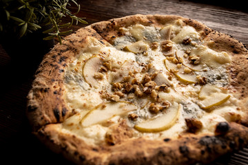Pizza z gruszką, orzechami i kozim serem na drewnianym, naturalnym, brązowym stole. Obok rozmaryn w doniczce - obrazy, fototapety, plakaty
