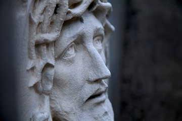 Ancient statue of Jesus Christ in profile against dark background. Religion, faith, death God concept.