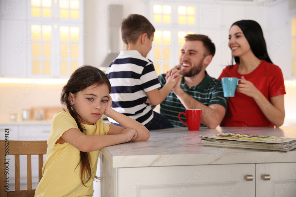 Wall mural Unhappy little girl feeling jealous while parents spending time with her brother at home