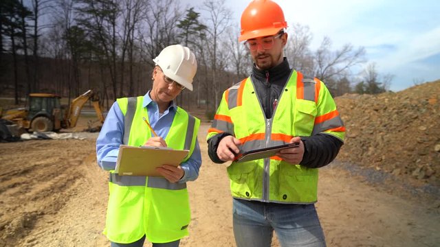Front view of woman project engineer and job foreman on a construction site discussing the building schedule.