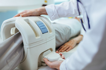 Close-up of medical technician preparing a patient for knee MRI scan.