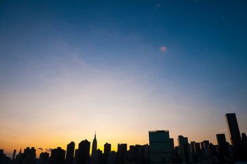 Scenic silhouette view of the Midtown Manhattan skyline in colorful dusk sunlight in New York City