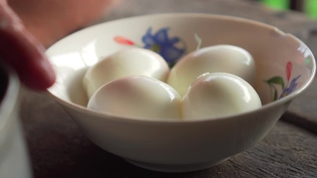 Old asian lady putting boiled egg on a bowl. slow motion. ready for cooking. ready for eating.