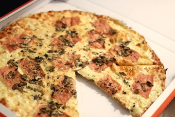 Pizza with cheese, ham and portobello mushrooms in a box. Selective focus.