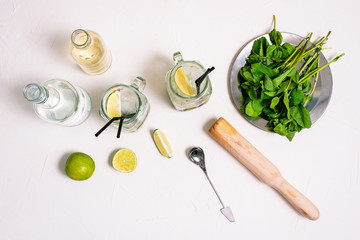 Ingredients for making a mojito cocktail. Slices of lime, mint leaves, syrup and rum on the table.