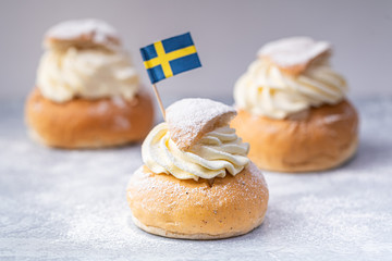 Traditional Scandinavian cream and almond paste filled cardamom bun Semlor with a Swedish flag.