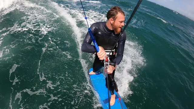 bearded man kitesurfing strapless in the waves