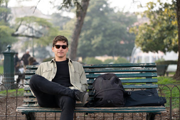 Young man sitting on a bench with a student backpack