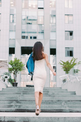 Back view young carefree fashionable woman in stylish denim jacket and dress having fun and running outdoors. Beautiful happy trendy hipster girl walking and posing on city streets. Youth and freedom