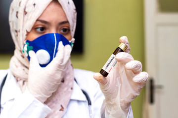doctor muslim woman wearing hijab and holding a positive blood test result for the new rapidly spreading Coronavirus, originating in Wuhan, China