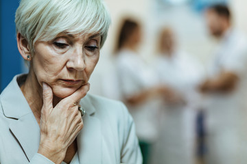 Fototapeta na wymiar Worried mature woman thinking of something in a hospital hallway.
