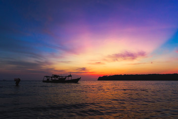 Amazing colorful sunset with fishing boat and fishing man in the water. trying to put all stuff on the boat. 