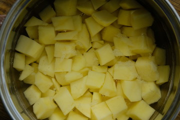 Sliced potatoes in water in a metal bowl