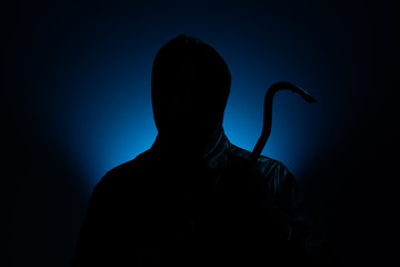 Vermummter Einbrecher mit Brecheisen im blauen Licht