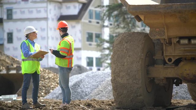 Construction site foreman shows tablet computer to woman architect regarding a construction project.